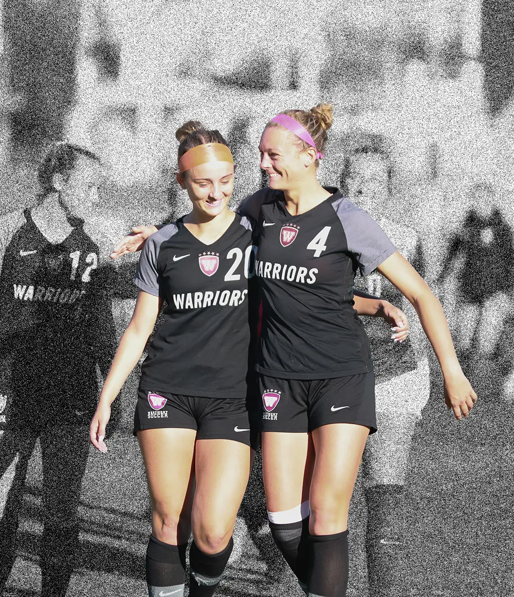 Two women's soccer players walking arm in arm