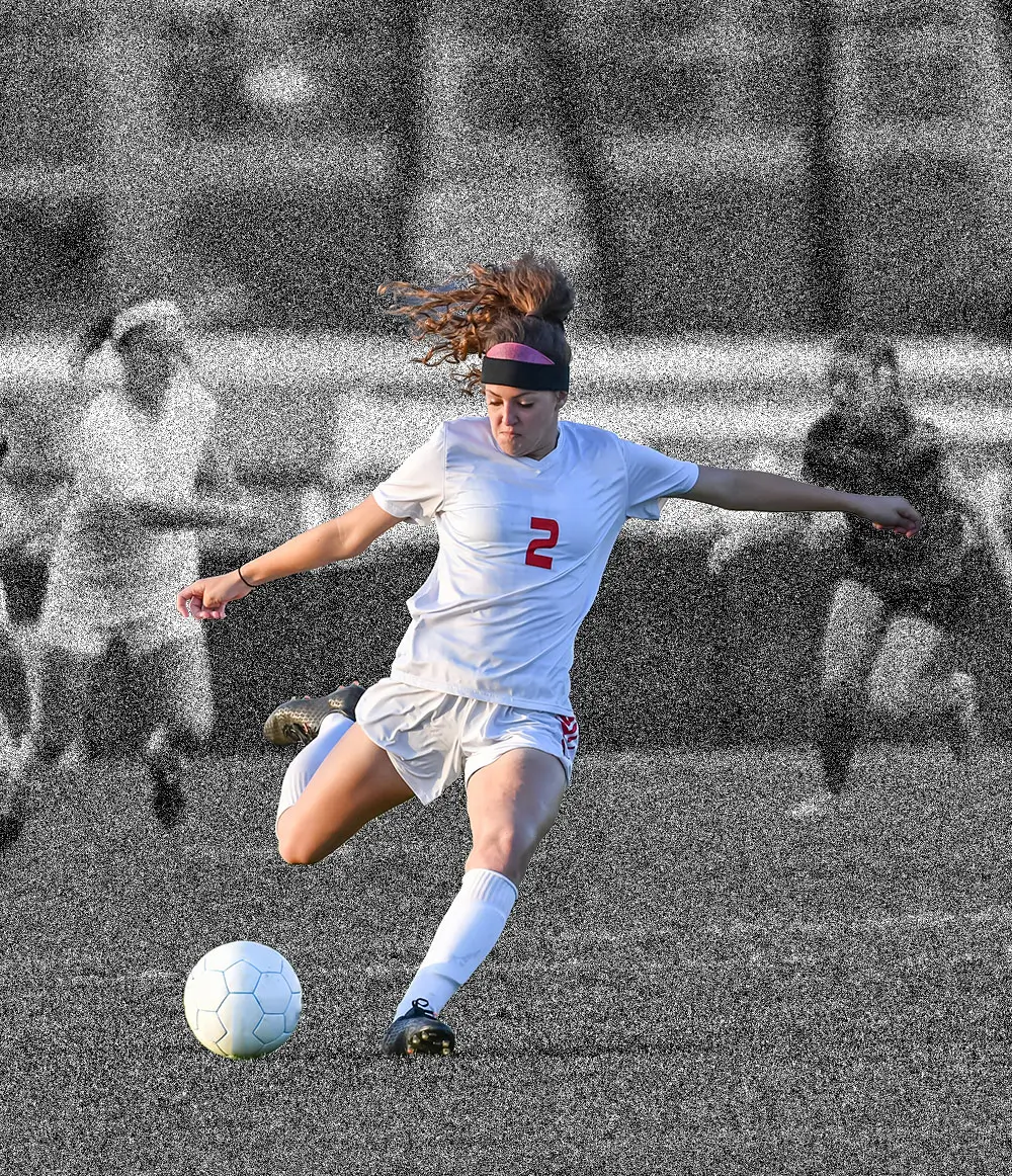 A women's soccer player striking the ball