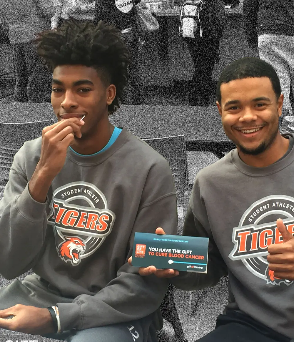Two student athletes swabbing their cheeks at a registry drive