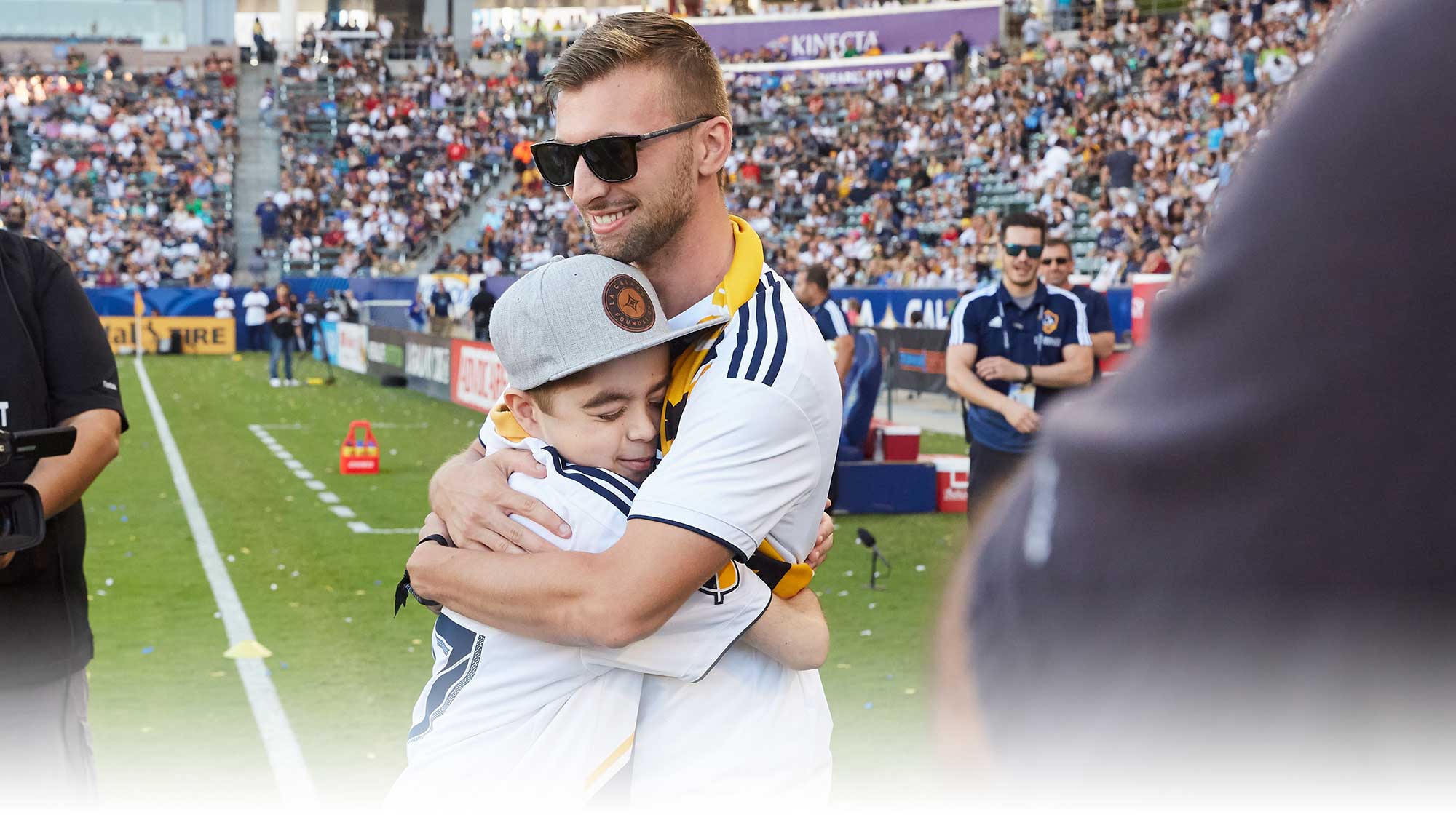 An LA Galaxy player hugs a young fan on the field